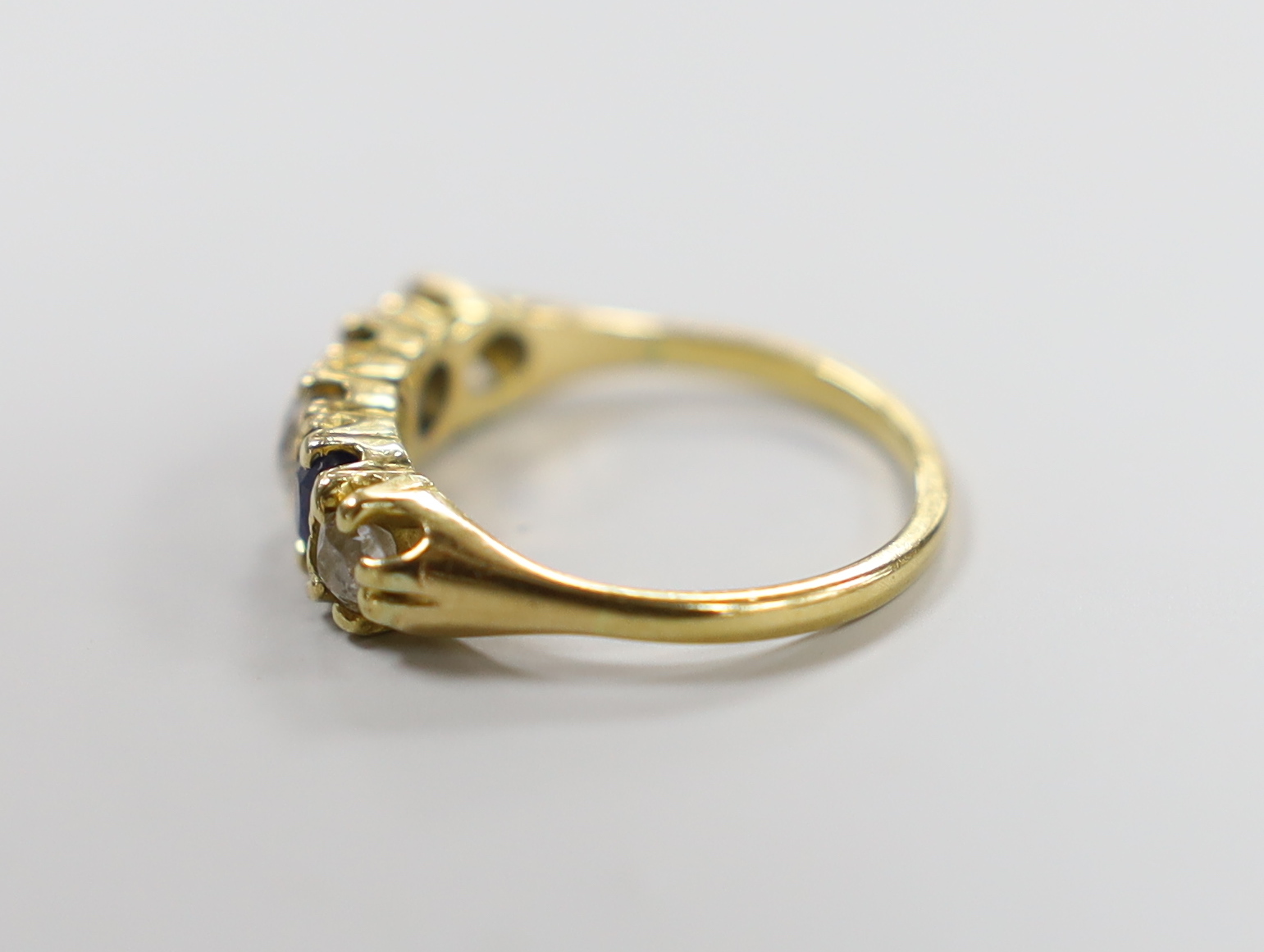 An 18ct, three stone diamond and two stone sapphire set half hoop ring, size M, gross weight 3.3 grams.